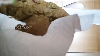 Woman takes a massive shit in a paper bag on the floor