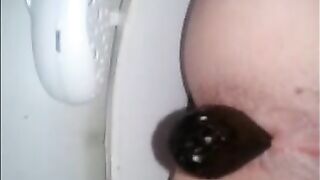 Shitting a dark turd in the toilet closeup
