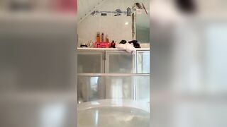 Naked woman squats over toilet while holding a tube of lube