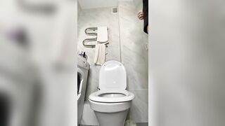 Woman sits on a toilet in high heels and leather shorts