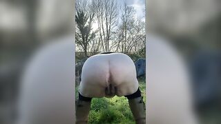 Man squats in the grass and shits on the ground.