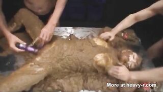 Women cover a naked woman in shit and fuck her with a dildo.