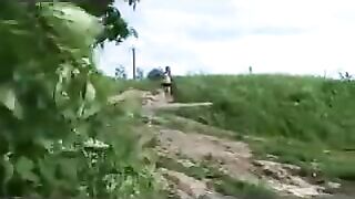 A woman takes a shit on a cross beam on the countryside