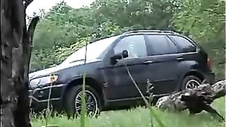 Girl pisses while bent over car tire