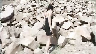 Girl squats and pisses on the rocks outside