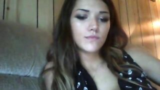 Brunette plays with her ass while sitting on the couch