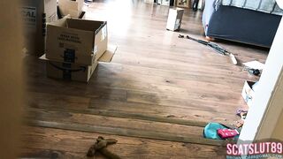Woman shits on the floor in living room next to boxes