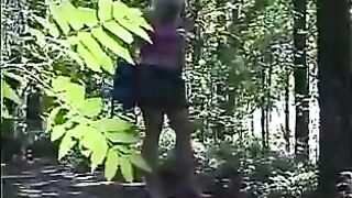 Girl takes a shit on the ground while standing in the woods