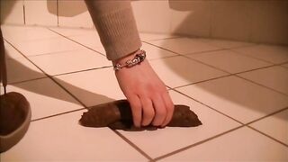 Girl shitting a very long turd on her hand standing
